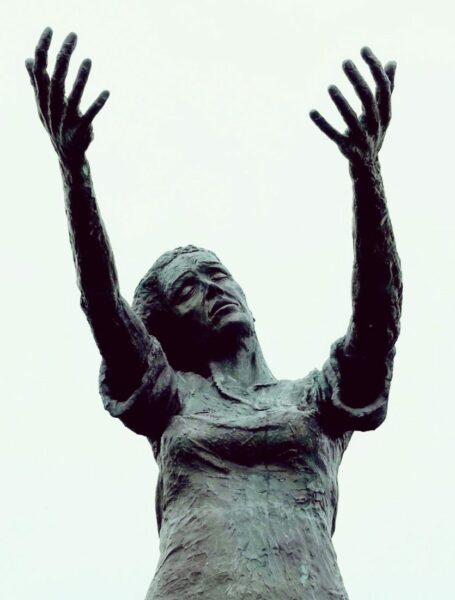 Frau mit sehnsuchtsvoll ausgestreckten Armen. Sinnbild für starke Emotionen, die sich im systemischen Erstgespräch zeigen können. Warten am Ufer – Bronzestatue in Rosses Point, Irland.