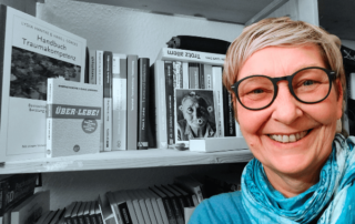 12 von 12 Oktober 2023: Sylvia vor ihrem Bücherregal.