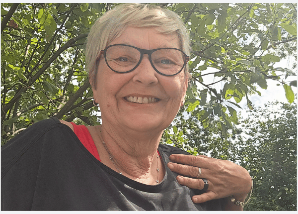 Frau sitzt ruhig und lächelnd unter einem Baum – radikale Selbstakzeptanz als innere Haltung